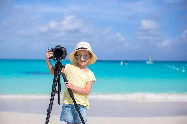 Portret van meisje met de camera op een statief aan witte zandstrand — Stockfoto