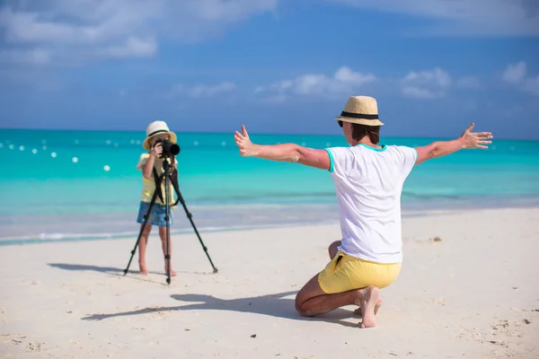 Piccola ragazza adorabile che fa foto del suo giovane padre sulla spiaggia esotica — Foto Stock