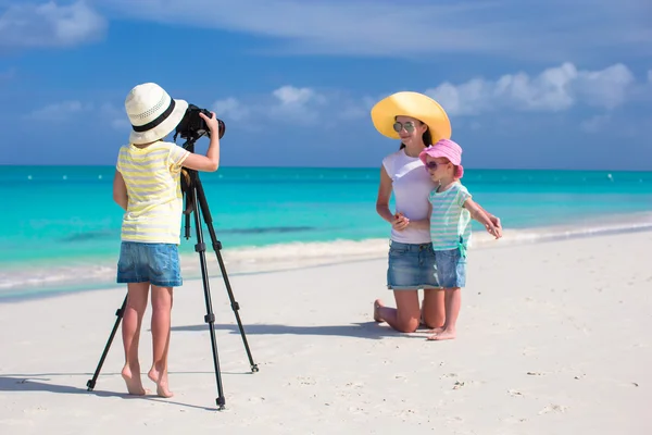 Маленькая милая девочка фотографирует свою семью на тропическом пляже — стоковое фото