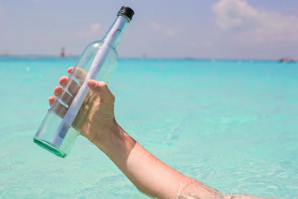 Bottle with a message in the hand background blue sky — Stock Photo, Image
