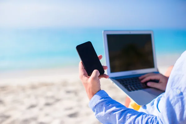 Bliska telefon na tle komputera na plaży — Zdjęcie stockowe