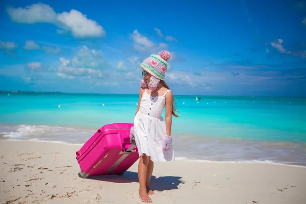 Entzückendes Mädchen mit warmem Winterhut und Fäustlingen, die mit Gepäck am Strand spazieren gehen — Stockfoto