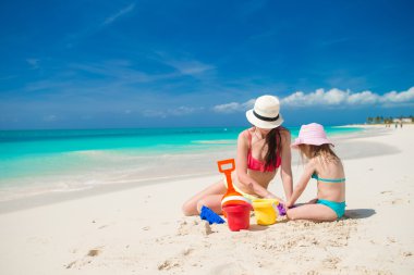 küçük sevimli kız ve genç anne bina sandcastle tropikal plaj