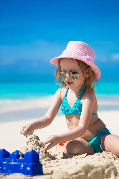 Очаровательная маленькая девочка играет с песком на идеальном тропическом пляже — стоковое фото