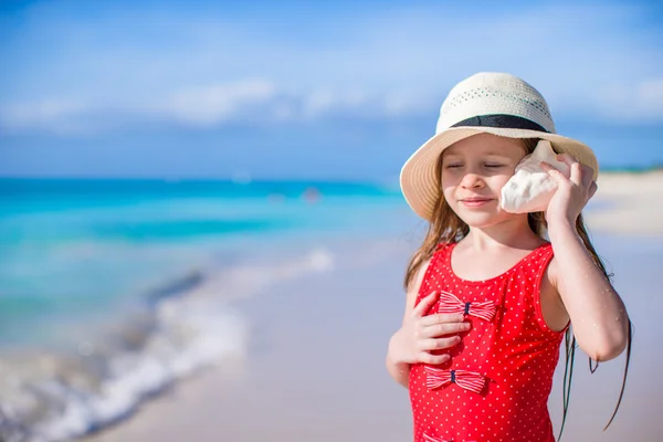 Kleines süßes Mädchen mit Muschel in den Händen am tropischen Strand — Stockfoto