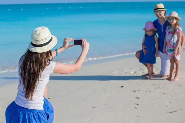 Young mother making photo on phone of her family at the beach — Stock Photo, Image