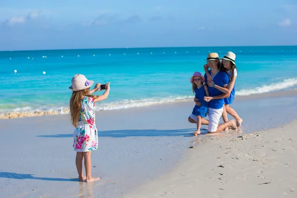 Little girl making photo on phone of her family at the beach — Stock Photo, Image