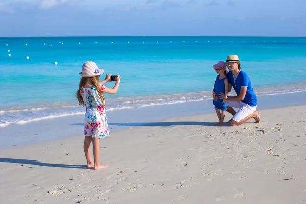 Little girl making photo on phone of her family at the beach — Stock Photo, Image