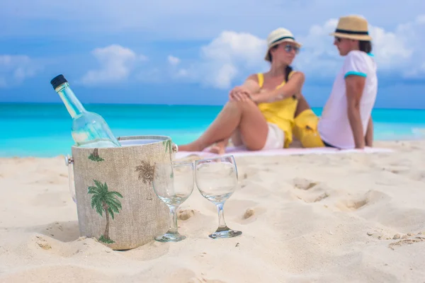 Butelka wina i dwie szklanki tło szczęśliwa para na plaży — Zdjęcie stockowe