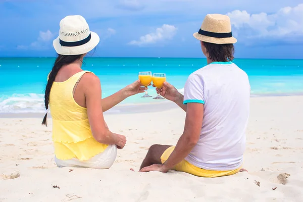 Couple heureux avec deux verres de jus d'orange sur une plage tropicale — Photo