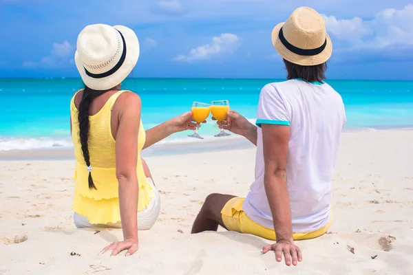 Ευτυχισμένο ζευγάρι με δύο ποτήρια χυμό πορτοκαλιού σε παραλία διακοπές — Φωτογραφία Αρχείου