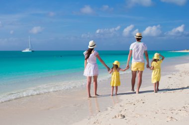 Back view young family of four on tropical beach clipart