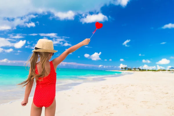 Tropikal bir plajda ellerinde kırmızı kalpli küçük kız — Stok fotoğraf
