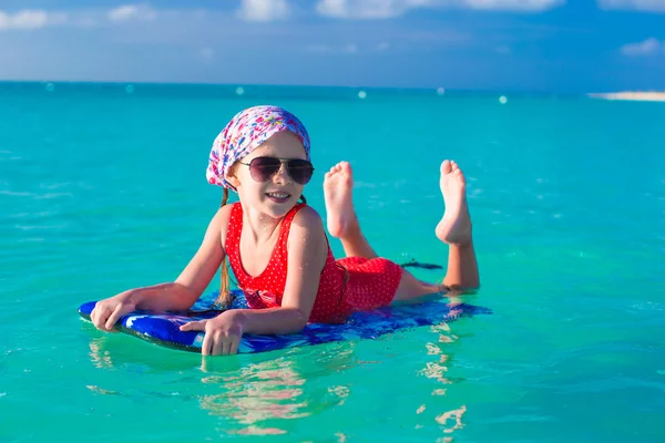 Little girl swimming on a surfboard in the turquoise sea — Stock Photo, Image