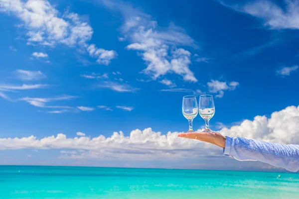 Two clean glasses at male hand on blue sky background — Stock Photo, Image