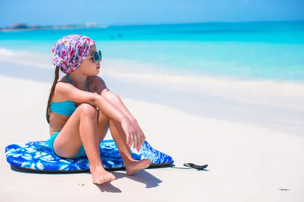 Bedårande liten flicka sitter på surfbräda på havsstranden — Stockfoto