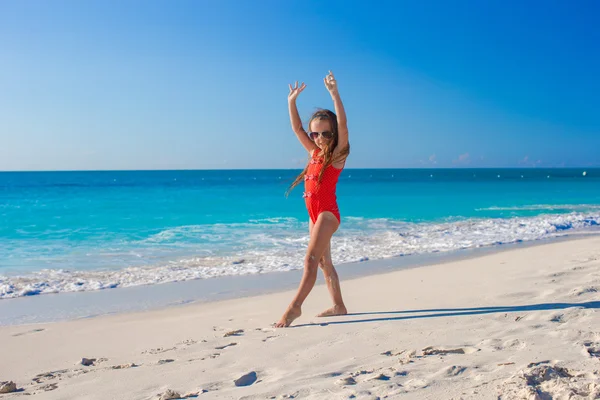 Милая гимнастическая девочка делает упражнения на тропическом пляже — стоковое фото