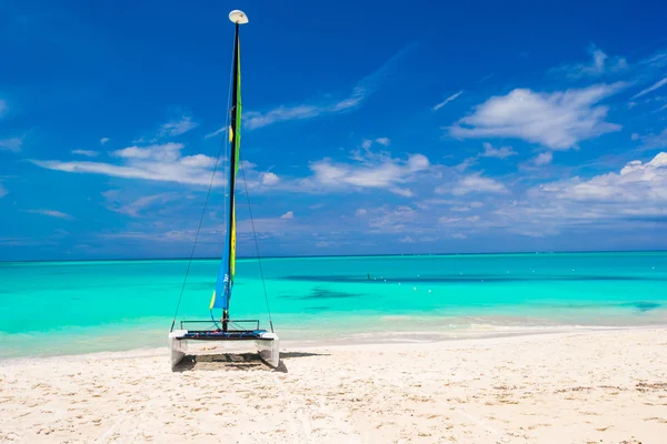 Катамаран з барвистим вітрилом на карибському пляжі — стокове фото
