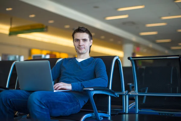 Young man with a laptop at the airport while waiting his flight — Stock Photo, Image