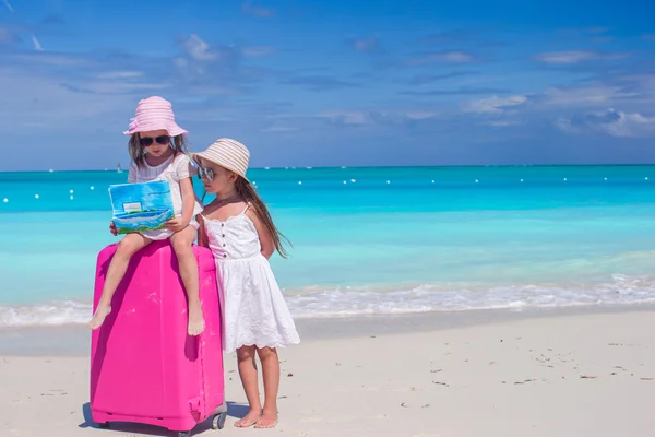 Kleine Mädchen mit großem Koffer und einer Landkarte auf der Suche nach dem Weg am tropischen Strand — Stockfoto