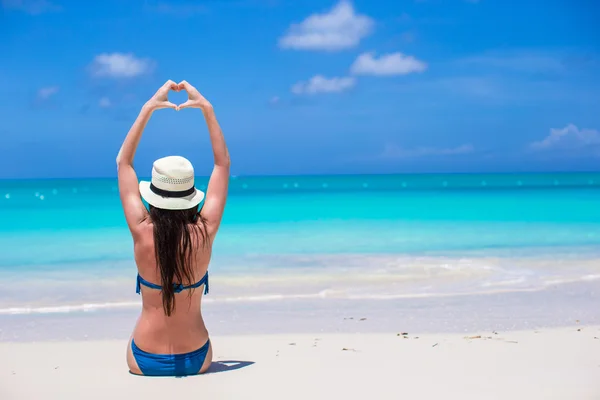 Attraktiv ung kvinna att göra ett hjärta med händerna på stranden — Stockfoto