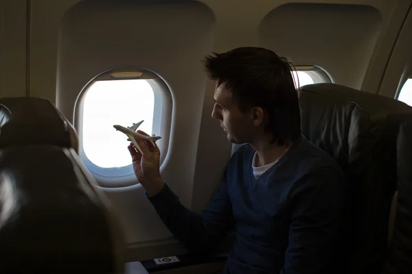 Молодой человек с маленьким самолетом модели внутри большого самолета — стоковое фото