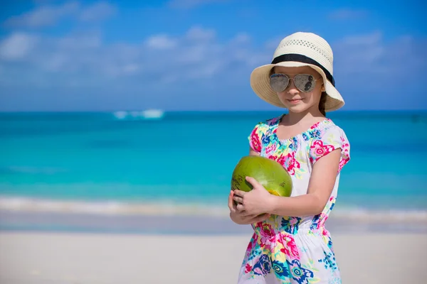 Entzückendes kleines Mädchen mit Kokosnuss am weißen Strand während der Sommerferien — Stockfoto