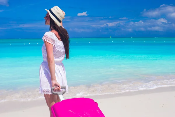 Back view of young happy woman with large luggage on tropical beach — Stock Photo, Image