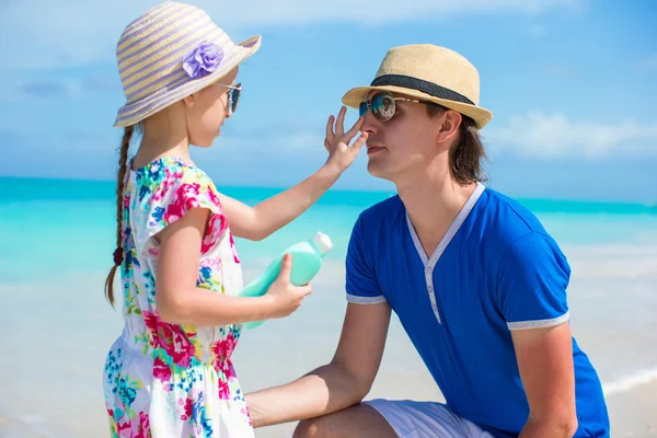 Klein meisje krijgt zonnebrandcrème op haar papa's neus — Stockfoto