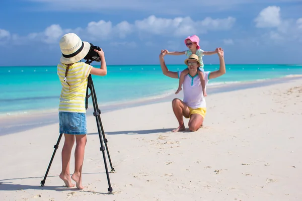 Маленькая девочка фотографирует своего отца и сестру на пляже — стоковое фото