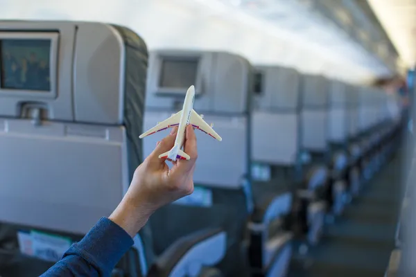 Feche a mão segurando um modelo de avião dentro de uma aeronave grande — Fotografia de Stock