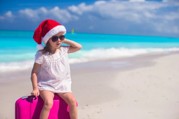 Kleines Mädchen mit Weihnachtsmütze und Koffer im Sommerurlaub — Stockfoto