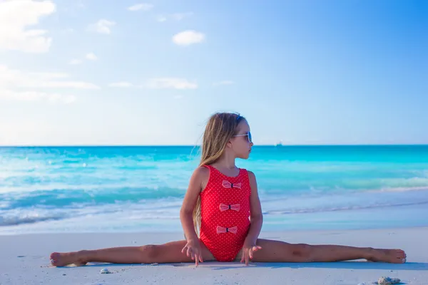 Little girl sitting on the splits at white sandy beach — Stock Photo, Image