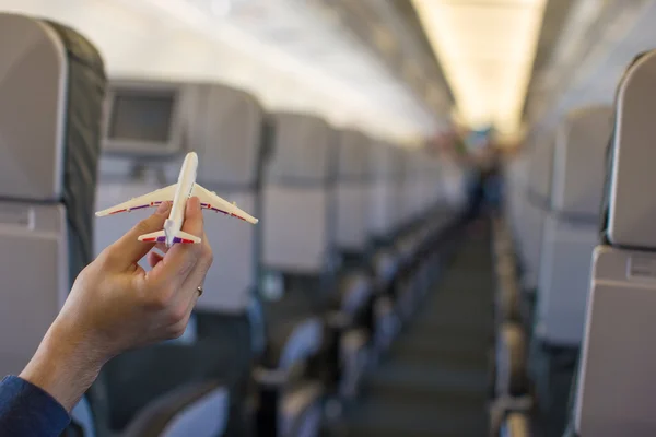 Close up hand holding an airplane model inside a large aircraft — Stock Photo, Image