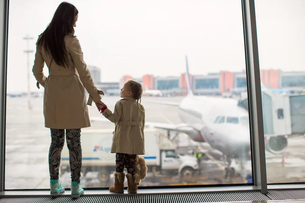 Mother and little daughter looking out the window at airport terminal — Stock Photo, Image