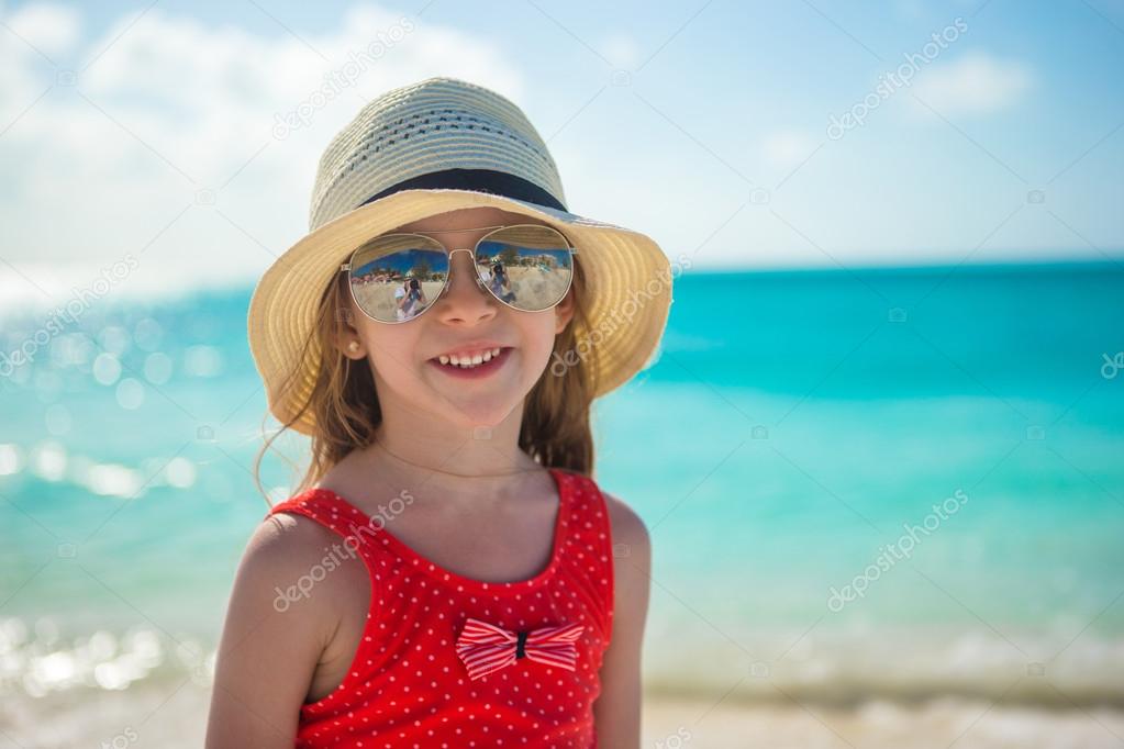 Happy little girl in hat on beach during summer vacation