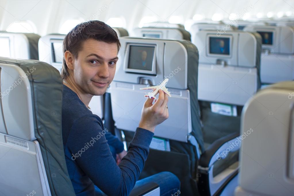 Happy man with small model airplane inside a large aircraft