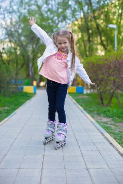 roller üzerinde küçük sevimli kız parkta kaymaktadır.