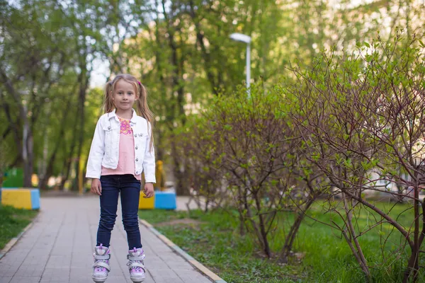 Красивая маленькая девочка на роликовых коньках в парке — стоковое фото