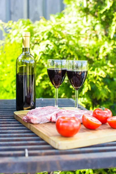 Juicy steak, vegetables and bottle of wine on a picnic outdoors — Stock Photo, Image