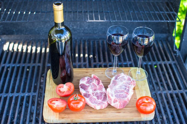 Dos copas de vino tinto, bistec y tomates en la barbacoa al aire libre —  Fotos de Stock