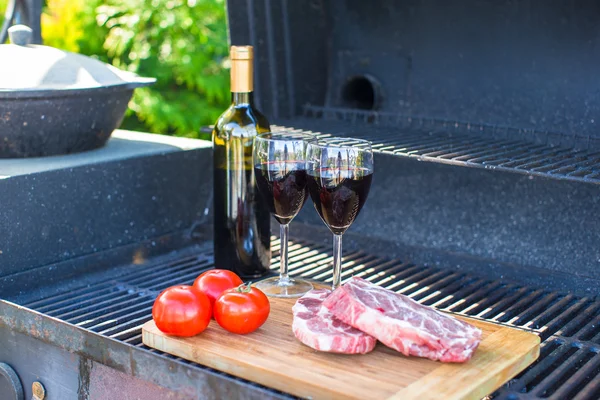 Fresh meat, vegetables and bottle of wine on barbecue outdoors — Stock Photo, Image