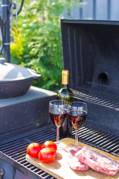 Fresh meat, vegetables and bottle of wine on barbecue outdoors — Stock Photo, Image