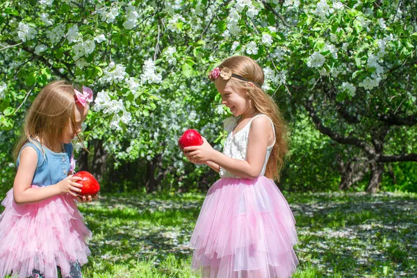 Adorables niñas con gran manzana roja en florecimiento huerto —  Fotos de Stock