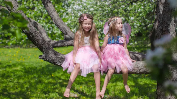 Bambine adorabili con ali di farfalla sul melo in fiore — Foto Stock