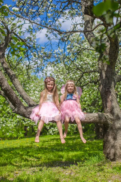 Kleine entzückende Mädchen sitzen auf blühendem Apfelbaum — Stockfoto