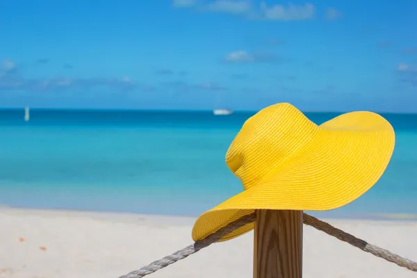 Żółty kapelusz na płocie na tropikalnej plaży biały — Stok fotoğraf