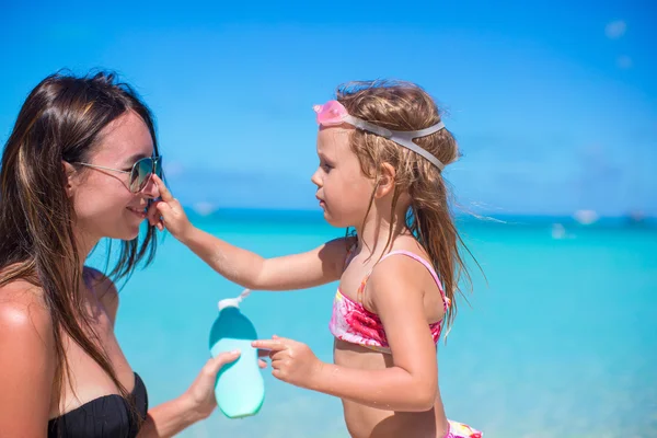 Маленька дівчинка отримує сонячний крем на носі матері — стокове фото