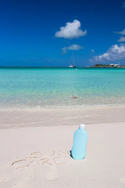 Suncare written on tropical white sand and suncream — Stock Photo, Image