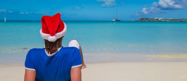 Visão traseira do jovem em santa hat na praia tropical do caribe — Fotografia de Stock